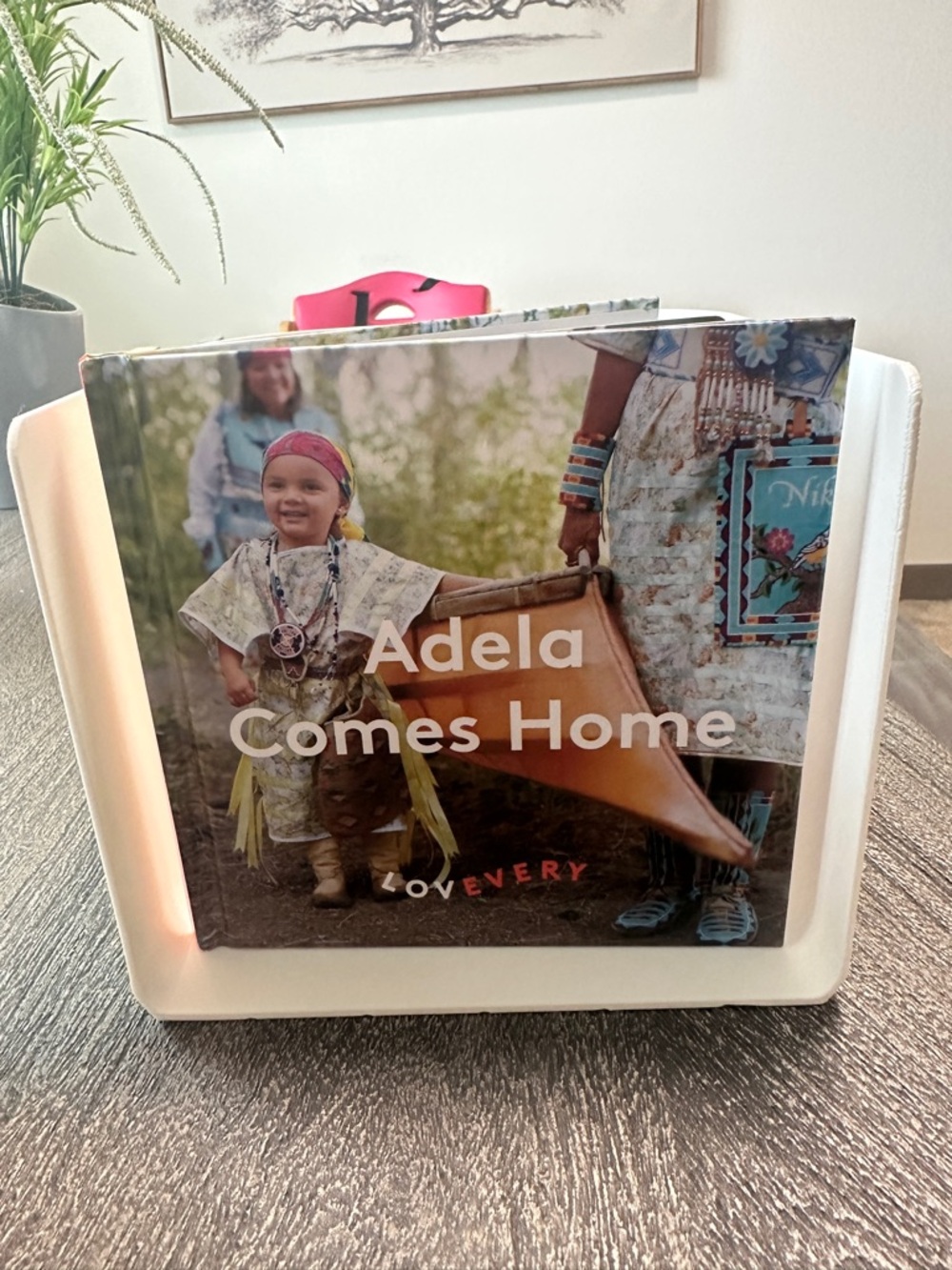 Adela Comes Home Kids Photo Book in White Display Stand by Lovevery